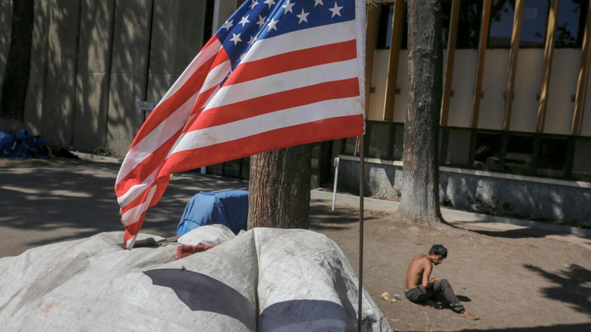 An American flag flies over a homeless encampment in the Civic Center Plaza in Santa Ana.