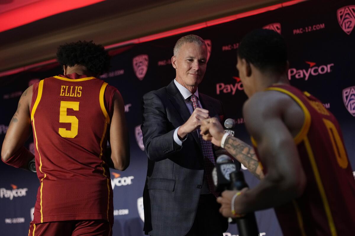USC coach Andy Enfield, center, greets Kobe Johnson during Pac-12 media day on Wednesday.