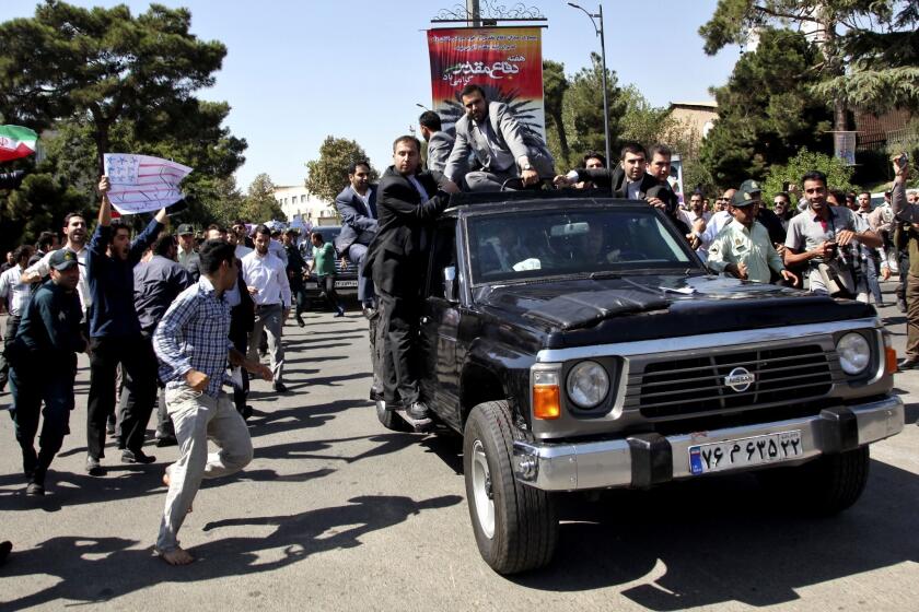 A protester, left, approaches President Hassan Rouhani's car leaving Mehrabad airport after his arrival from the U.S. in Tehran on Saturday.