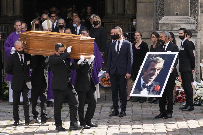 Alguien sostiene una foto de Jean Paul Belmondo durante las ceremonias fúnebres del actor francés en París el 10 de septiembre del 2021. (AP Photo/Michel Euler)