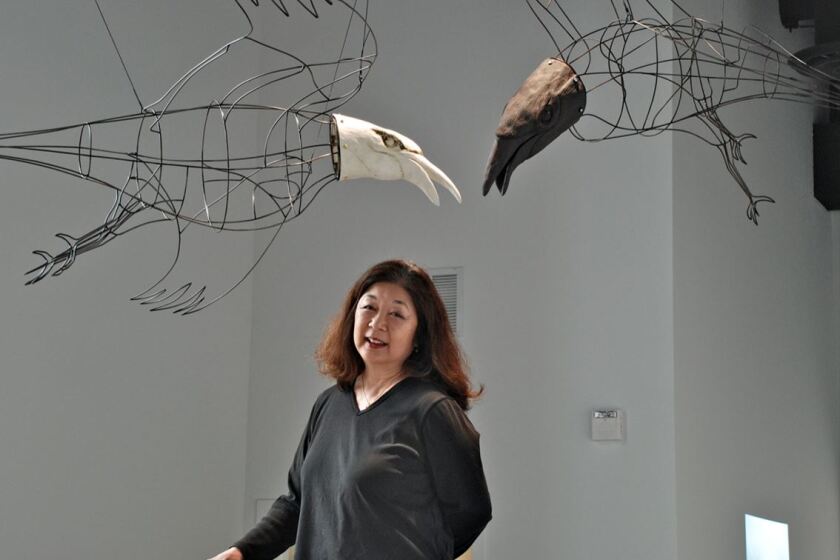 Joanne Hayakawa standing in front of an art piece in her studio “Malady and Misdirection.”