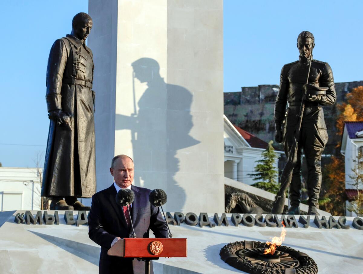 Russian President Vladimir Putin delivers his speech in front of a memorial of statues and an eternal flame