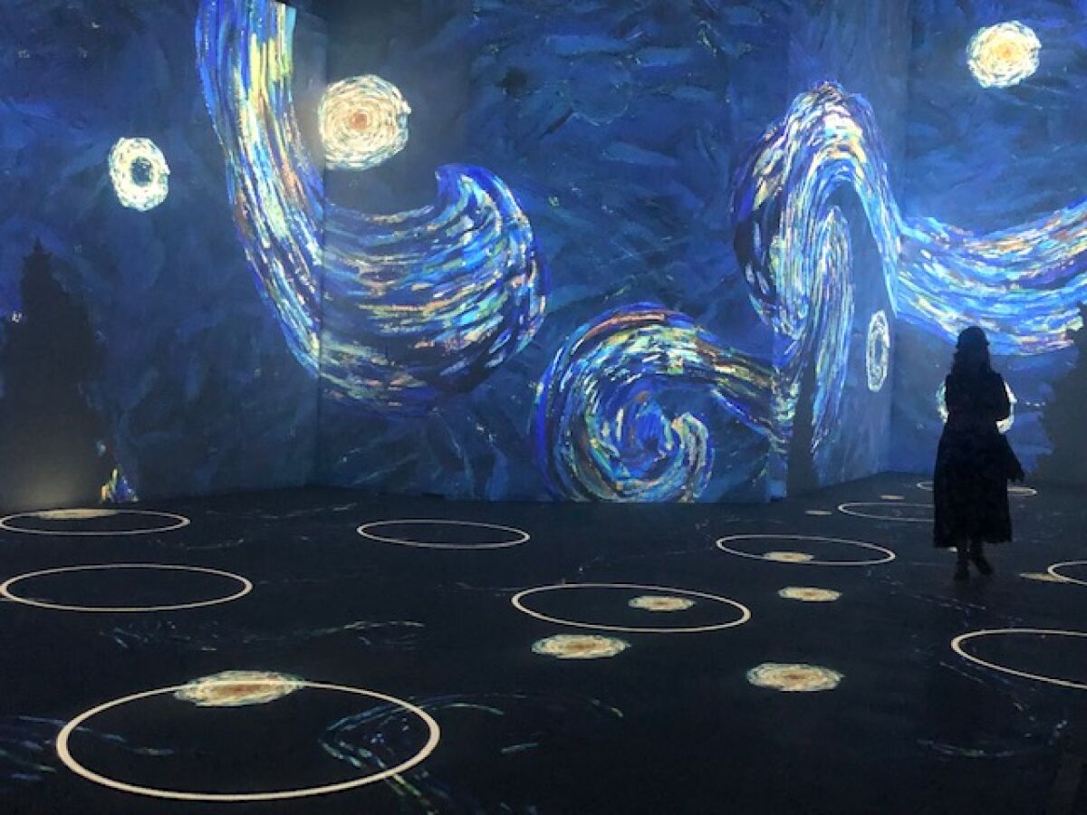 A person stands in a room with walls with blue swirls of paint and a floor with outlined white circles.