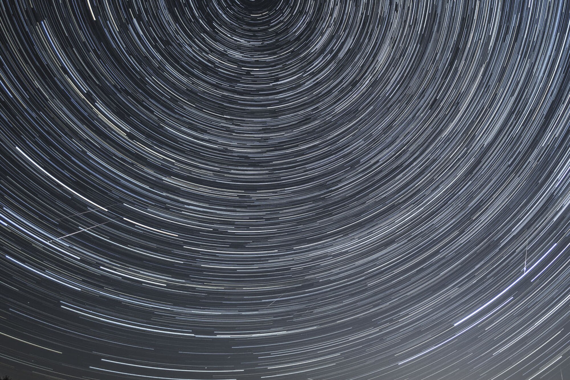 Composite image of stars and meteors in transit across the night sky.