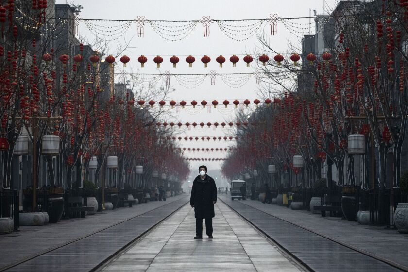 A man walks in a nearly empty and shuttered commercial street in Beijing on Wednesday.
