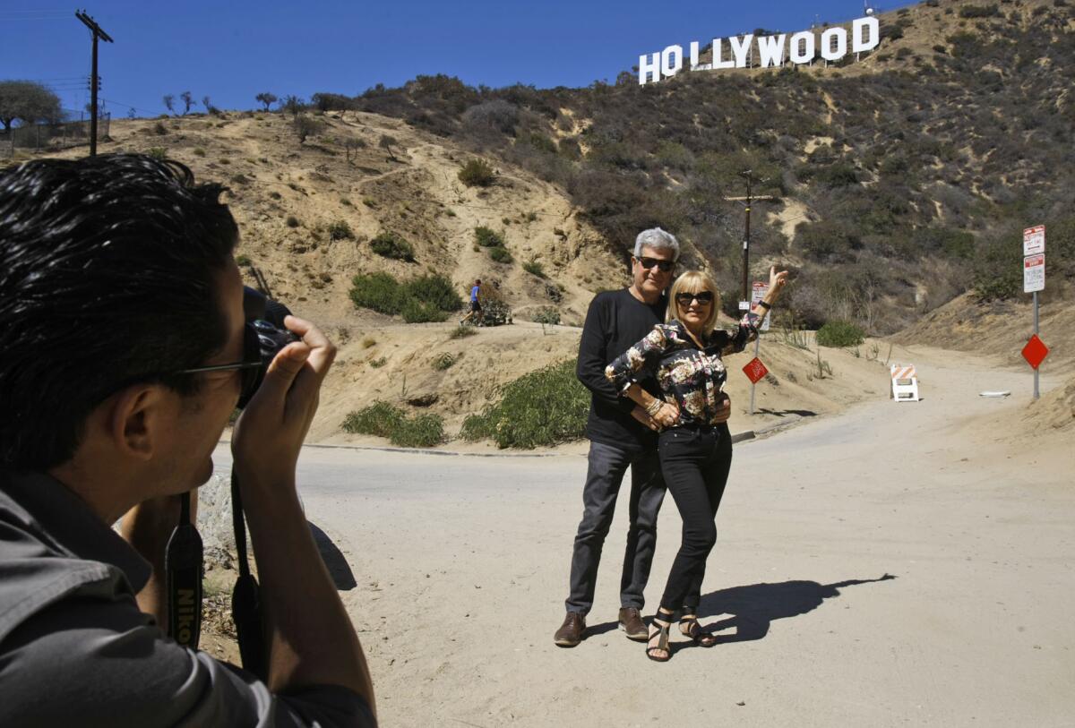Tourists from Spain have their picture taken in front of the Hollywood sign. A nearby trail head will be closed for about five weeks so the city can build a new, more secure gate.