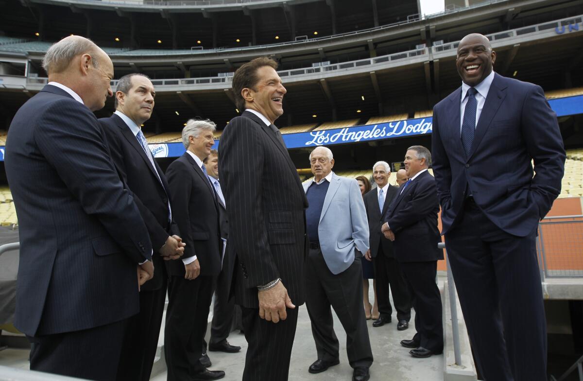 Peter Guber, center, and Magic Johnson, right, before a press conference announcing their Guggenheim group as the new owner of the Dodgers in 2012.