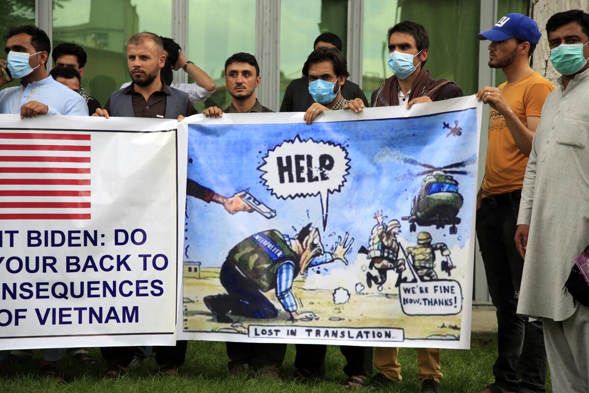 Afghan interpreters hold banners, including one with a political cartoon showing the U.S. military abandoning them