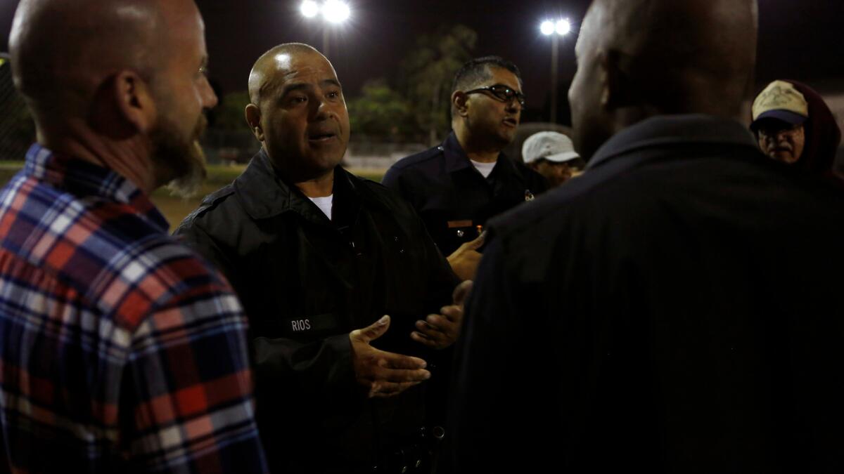 LAPD officers Oscar Casini, center left, and Roger Medina, center right, talk with Boyle Heights area residents during a Summer Night Lights program at the Costello Recreation Center in Boyle Heights.