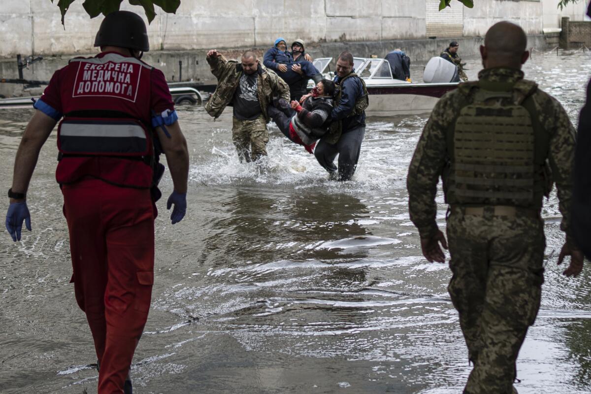 Emergency teams walk through flooding carrying an injured civilian who came under fire from Russian forces.