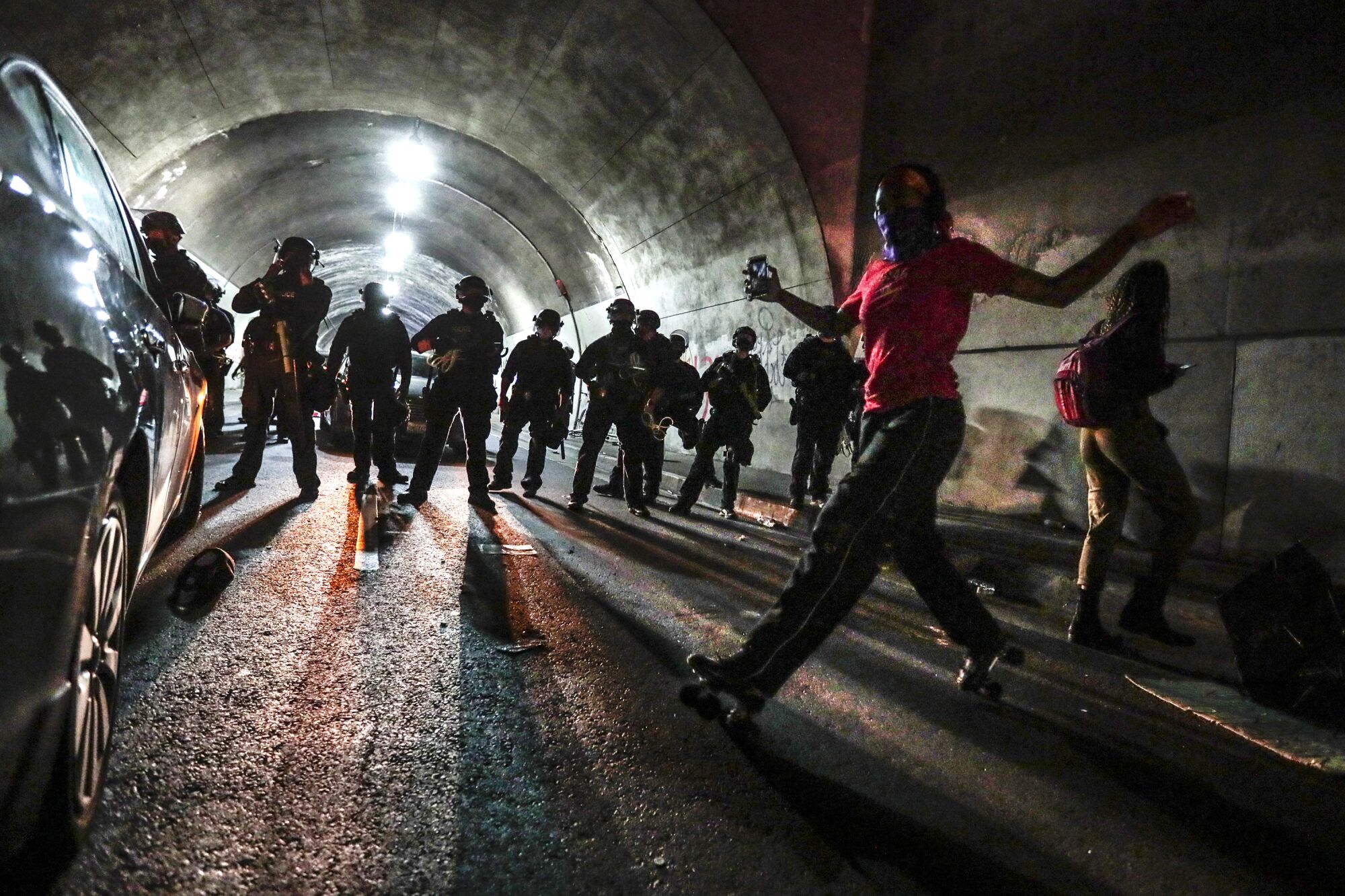 Liliana Ruiz roller skates in front of LAPD officers in the 3rd Street tunnel. 