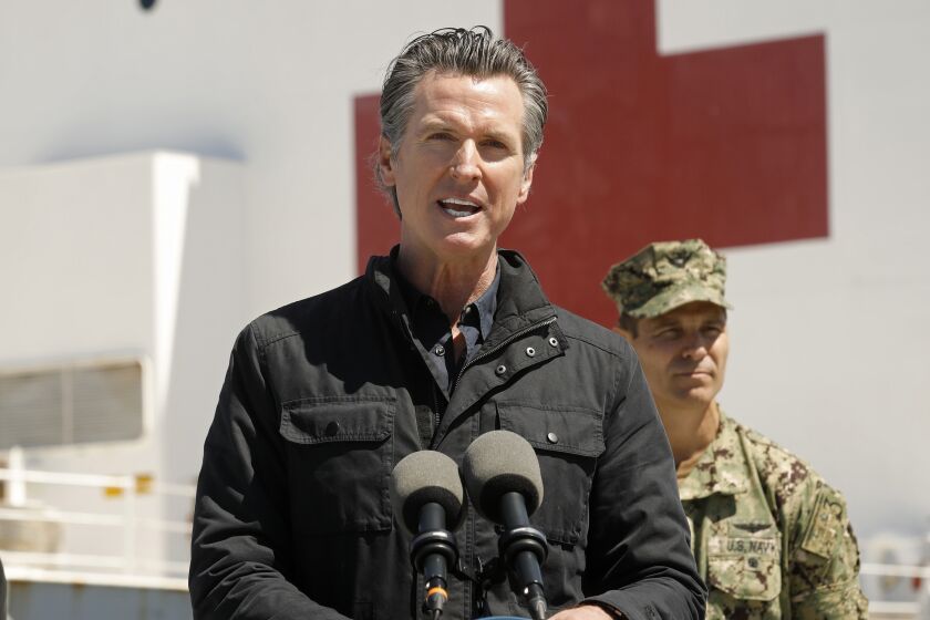 LOS ANGELES, CALIFORNIA-MARCH 27, 2020-California Governor Gavin Newsom speaks in front of the hospital ship USNS Mercy that arrived into the Port of Los Angeles on Friday, March 27, 2020, to provide relief for Southland hospitals overwhelmed by the coronavirus pandemic. Also attending the press conference are Mayor Eric Garcetti, left, Dr. Mark Ghaly, Secretary of Health and Human Services,, Director Mark Ghilarducci, Cal OES, Robert Fenton, FEMA Regional Administrator for Region 9, admiral John Gumbleton, United States Navy, Captain Brian Quin, United States Navy and Captain Monica Rochester, United States Coast Guard and Captain of the Port. (POOL PHOTOGRAPHS BY Carolyn Cole/Los Angeles Times)