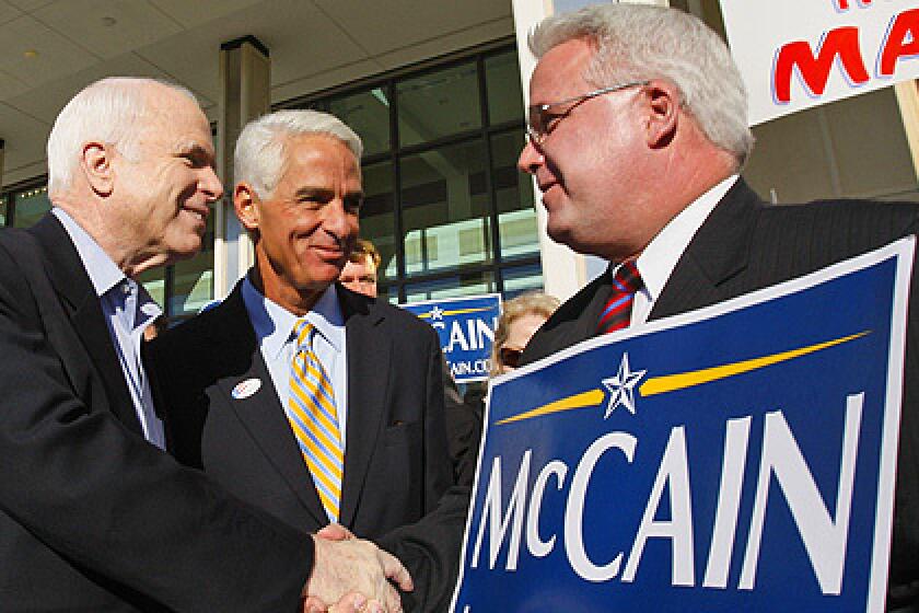 Republican presidential hopeful, Sen. John McCain, R-Ariz., left, accompanied by Florida Gov. Charlie Crist, center, greets a supporter during a visit to a polling station in St. Petersburg, Fla.