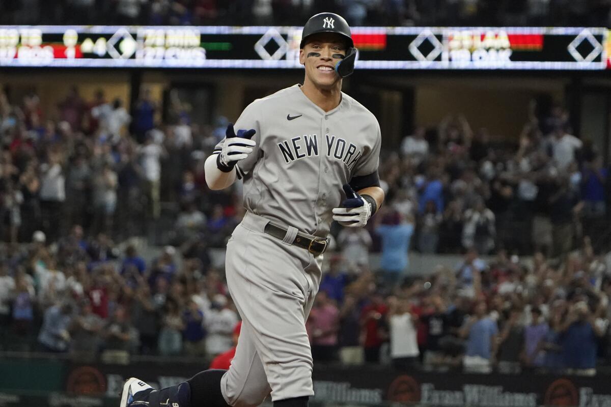 Aaron Judge smiles and points as he rounds the bases. 