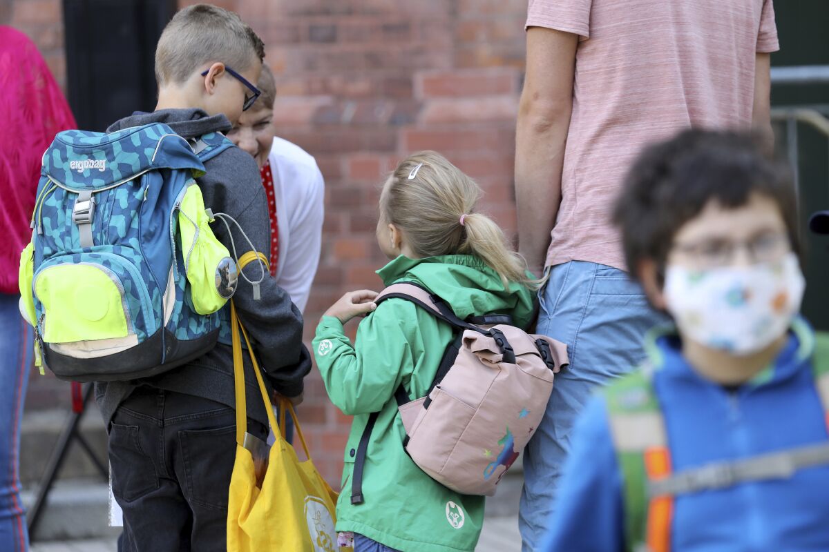 Students are brought to school by their parents in Rostock, Germany Monday, Aug. 3, 2020 as Mecklenburg-Western Pomerania is the first federal state to resume regular school operations throughout the state. About 150,000 students are expected to attend their schools. (Bernd W'stneck/dpa-Zentralbild/dpa via AP)