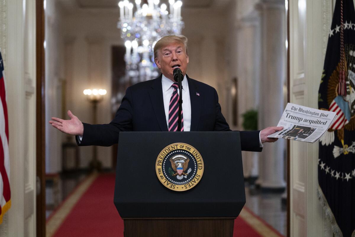 FILE - President Donald Trump holds up a newspaper with a headline that reads "Trump acquitted" during an event celebrating his impeachment acquittal, in the East Room of the White House, Feb. 6, 2020, in Washington. The impeachment investigation, sparked by a government whistleblower's complaint over Trump's call, swiftly became a milestone, the first in a generation since Democrat Bill Clinton faced charges over an affair with a White House intern. (AP Photo/Evan Vucci, File)