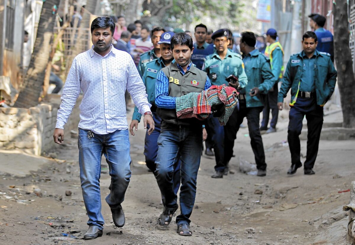A member of a bomb disposal unit carries away homemade bombs during a raid on a building where members of a banned Islamist group were detained in Dhaka, Bangladesh, in December 2015.