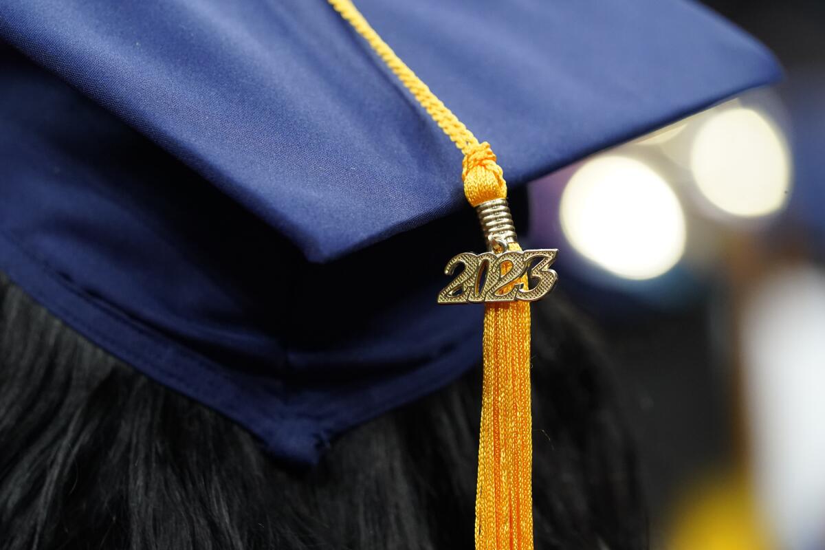 A tassel with 2023 on it rests on a graduation cap 