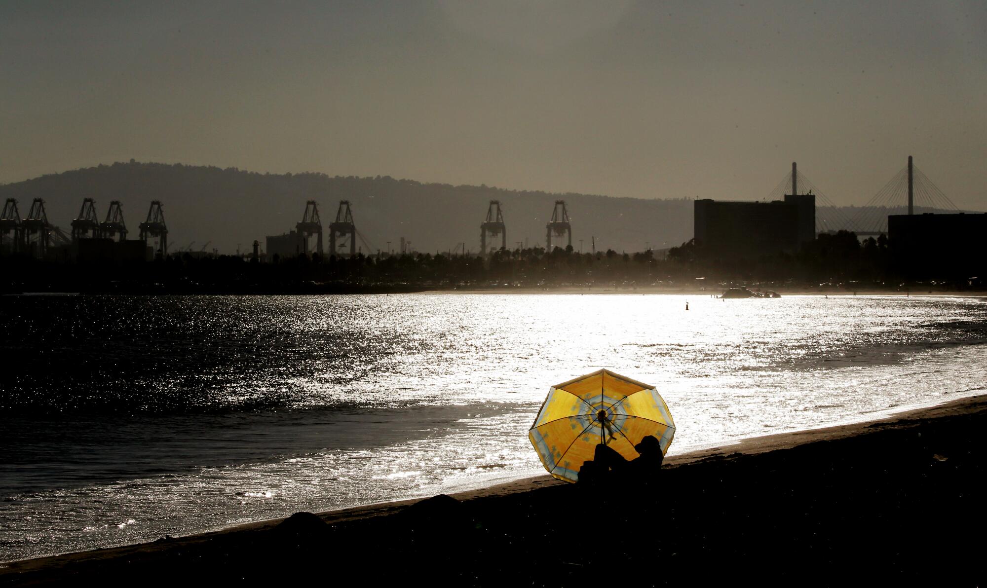 A beachgoer shelters from the hot sun under an umbrella at Junipero Beach in Long Beach