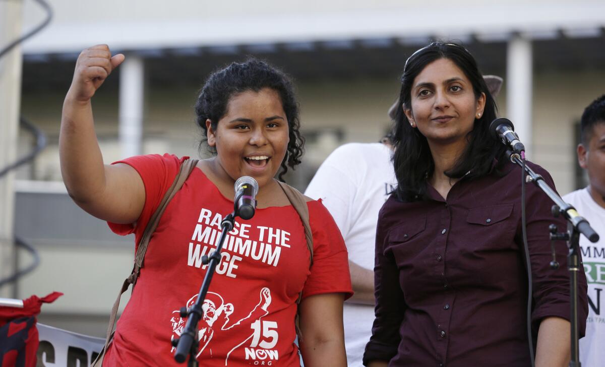 Seattle City Council Member Kshama Sawant, right, looks on as Stephanie Sucasaca holds up a fist as Sawant had just done while interpreting Sawant's remarks into Spanish on May Day.