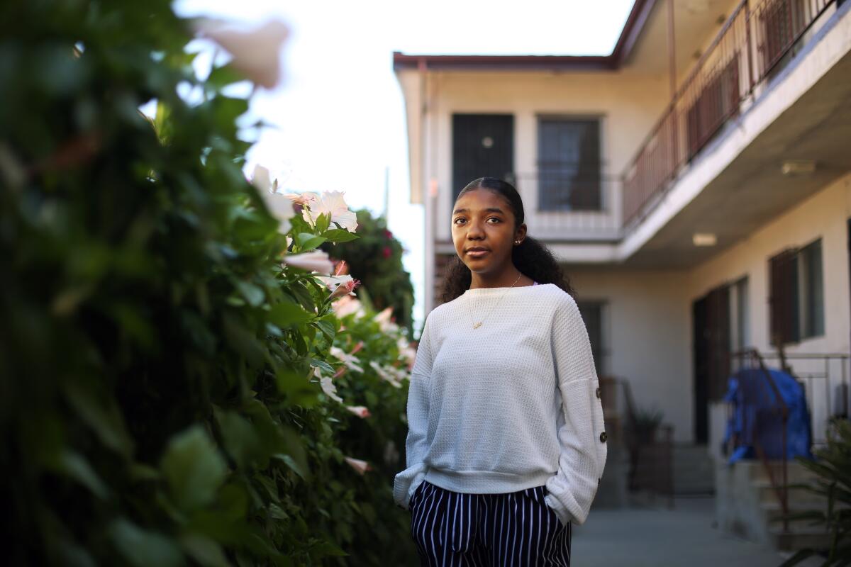 Kahlila Williams, a senior at Girls Academic Leadership Academy, poses by a hedge in an apartment building's courtyard.