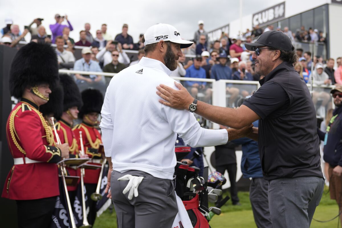 Dustin Johnson and Phil Mickelson greet each other on the first tee at the inaugural LIV Golf Invitation in England.