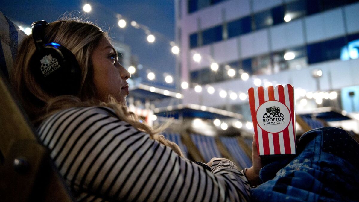 April Torres settles in her seat before Martin Scorsese's "Goodfellas" on the roof at Hollywood's Montalban Theater. The Rooftop Cinema Club offers iconic movies complete with outdoor seating, wireless headphones and a rooftop bar, all under the California sky.