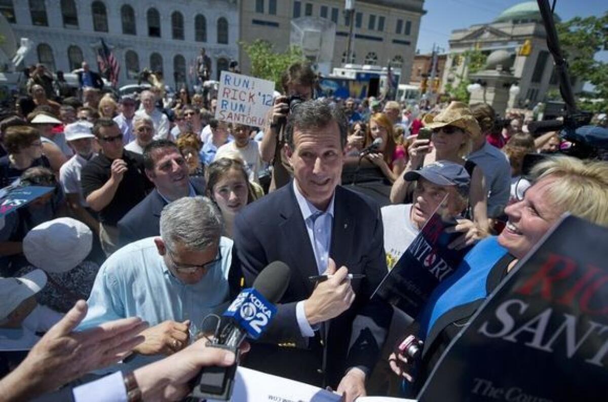 Rick Santorum speaks with a reporter as he mingles with the crowd after announcing his presidential candidacy.
