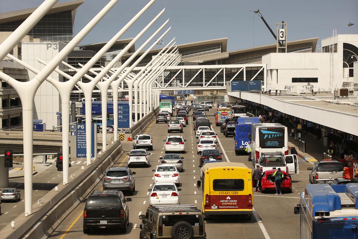 Vehicle and bus traffic moves through the LAX terminal drop-off areas. 