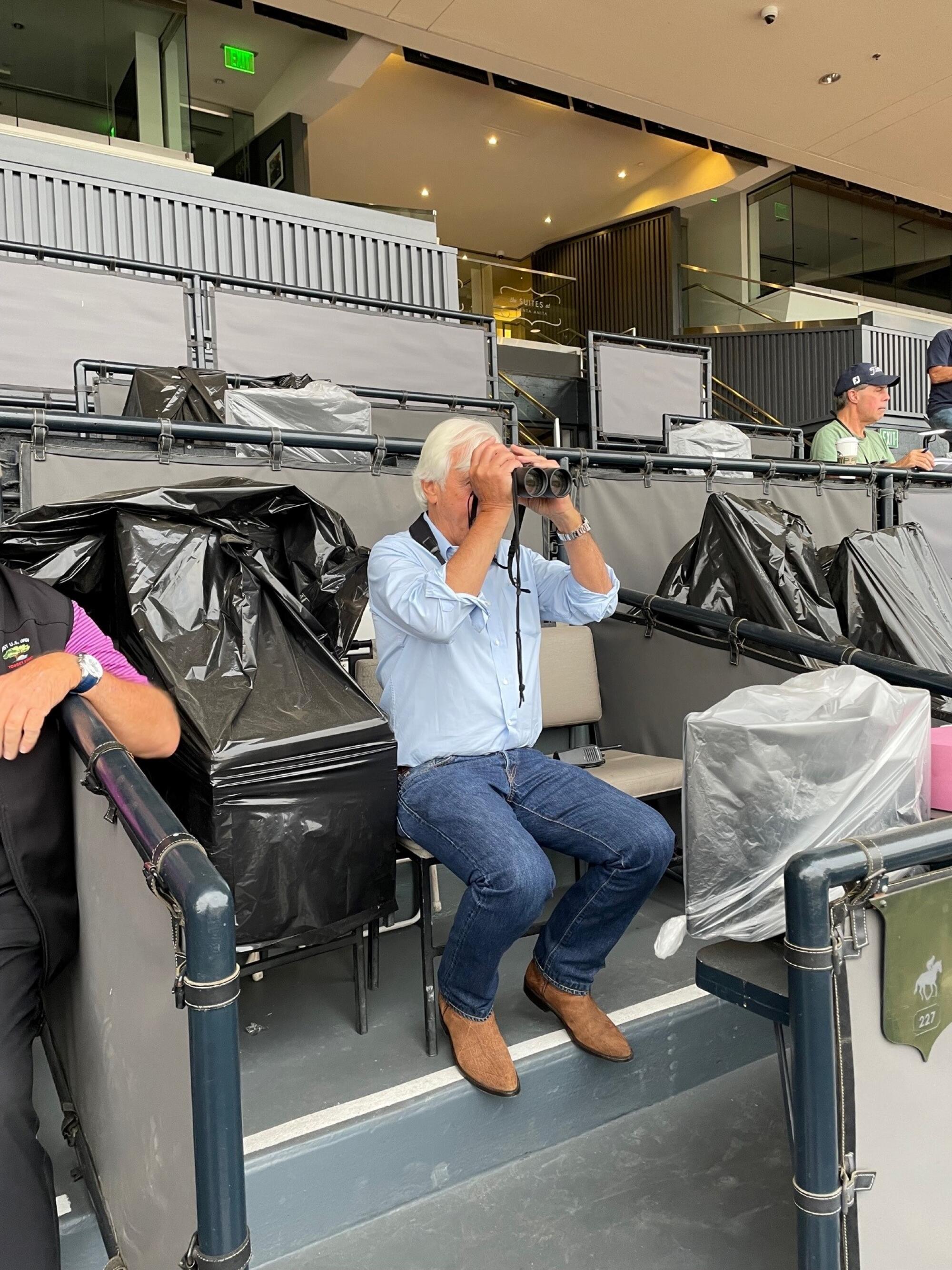 Trainer Bob Baffert uses binoculars to watch horses work out at Santa Anita Park on Sunday.