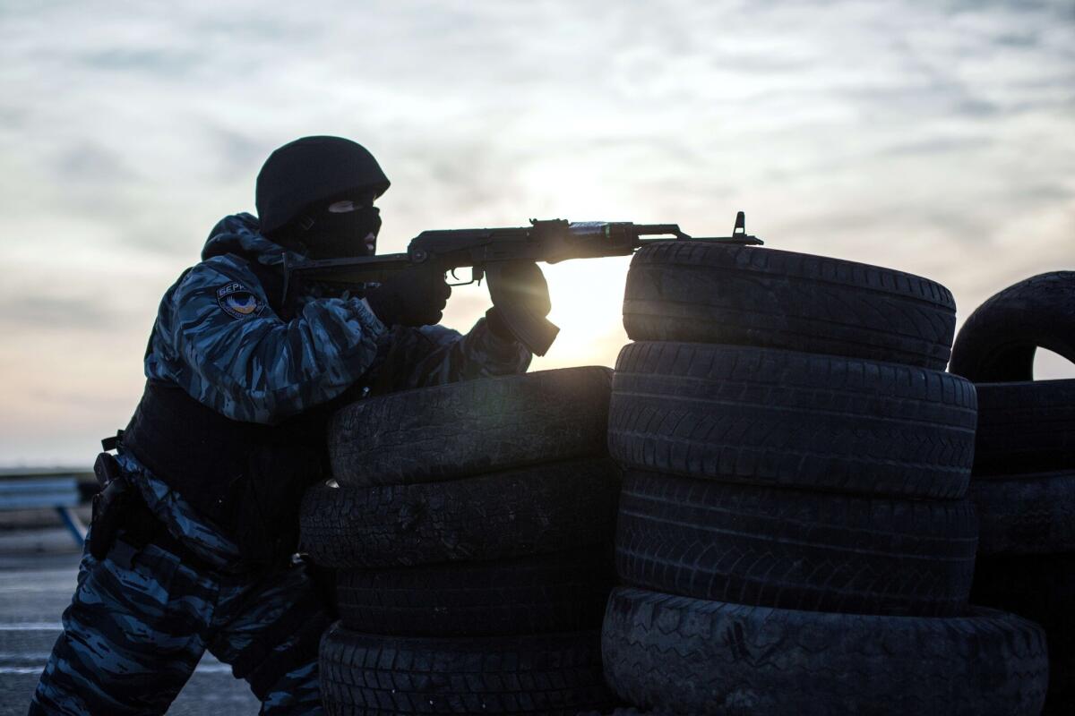 A pro-Russia service member stands guard at a checkpoint in Chongar, blocking an entry point into Crimea, southern Ukraine.