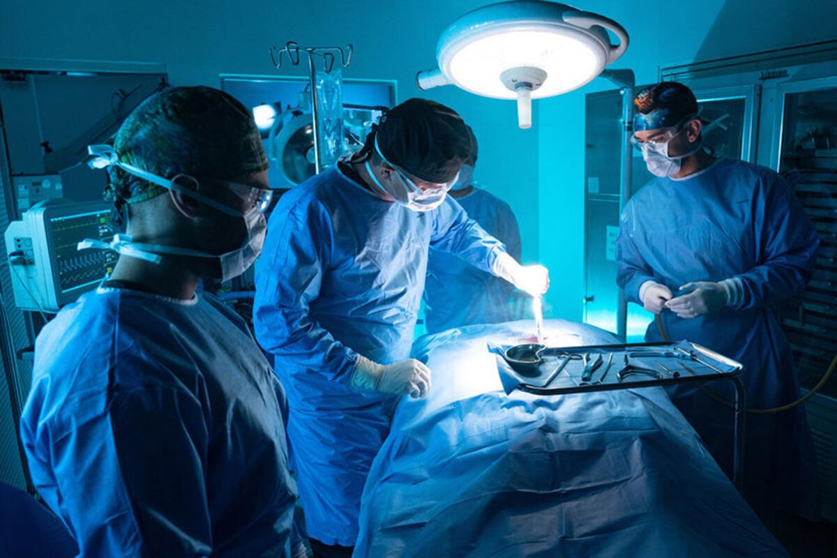 Three people in scrubs in an operating room