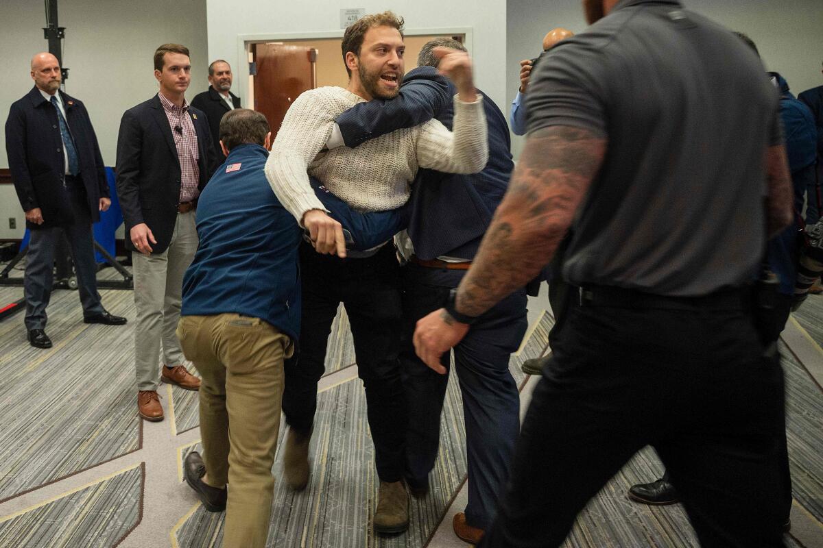 A protester is dragged from the room as Donald Trump Jr. speaks with his brother Eric during a "Keep Iowa Great" press conference in Des Moines, IA.