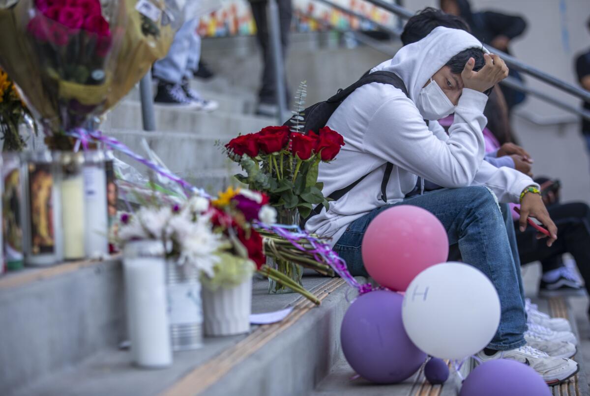 A student sits next to a memorial on steps