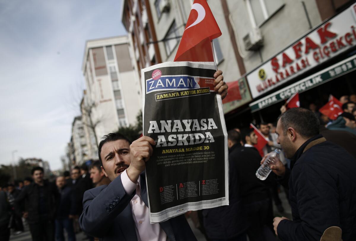 A man holds Saturday copy of the newspaper Zaman with the headline " the constitution suspended "as people gathered in support outside the paper's headquarters in Istanbul on March 6.