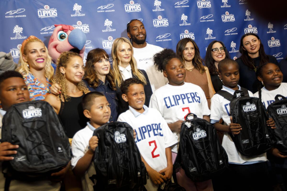Clippers Kawhi Leonard stands with representatives from Baby 2 Baby as he gives backpacks away to students at One Hundred Seventh Street Elementary School on Tuesday in the Watts neighborhood of Los Angeles.