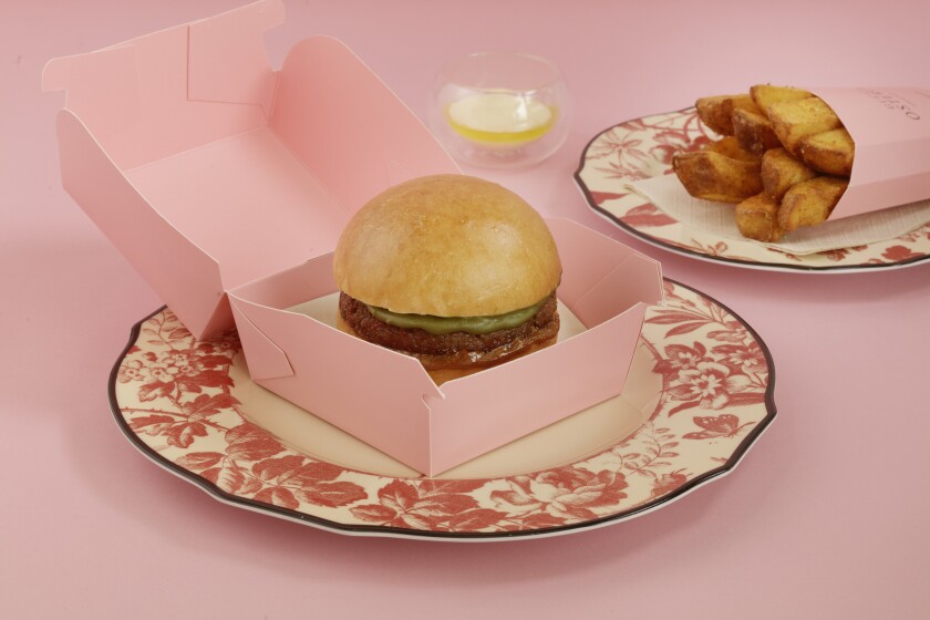 A burger in a pink box and fries in a pink box on fancy red-and-white china.