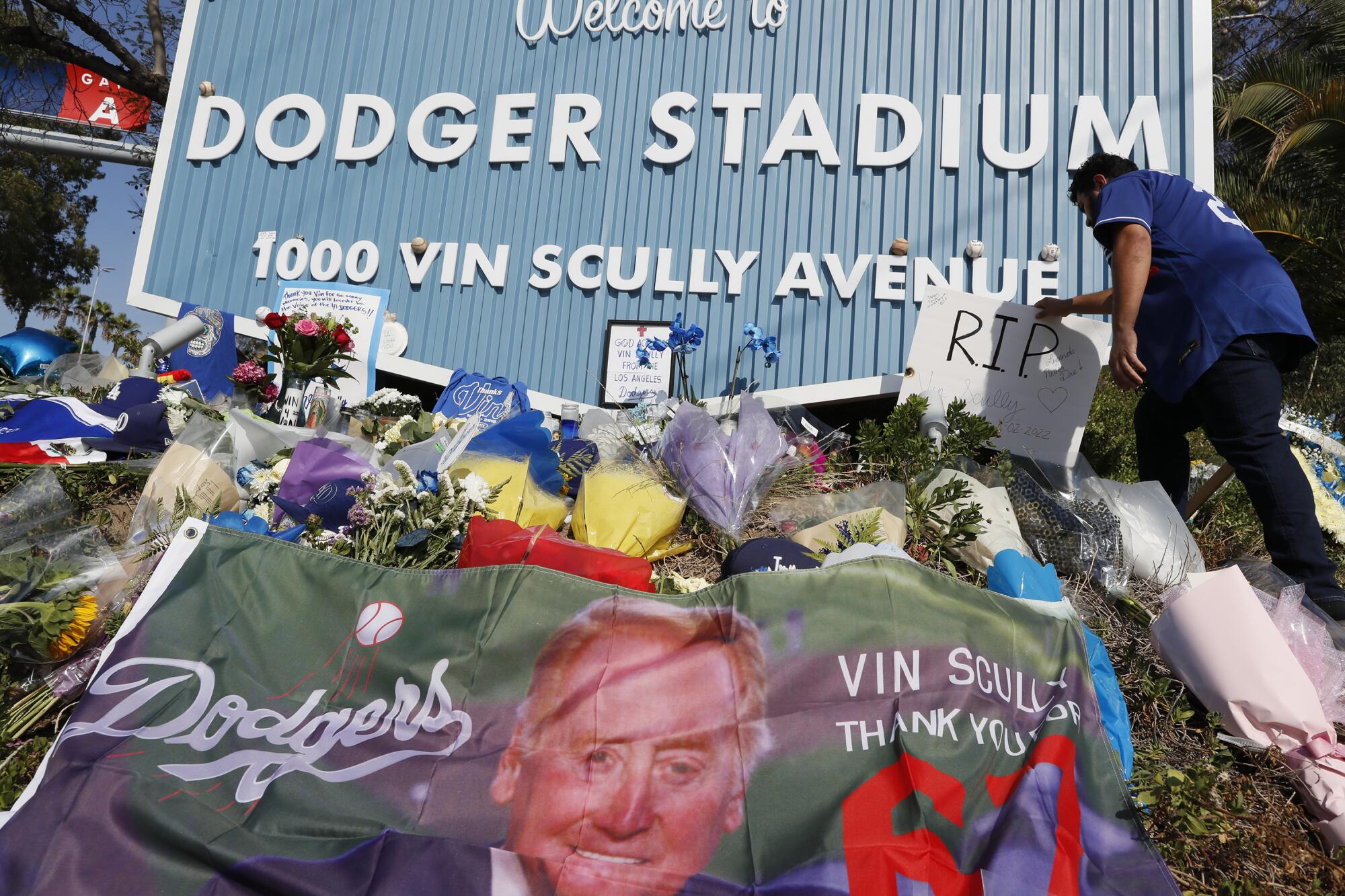 Javier Najera places a handmade sign at the memorial outside Dodger Stadium 