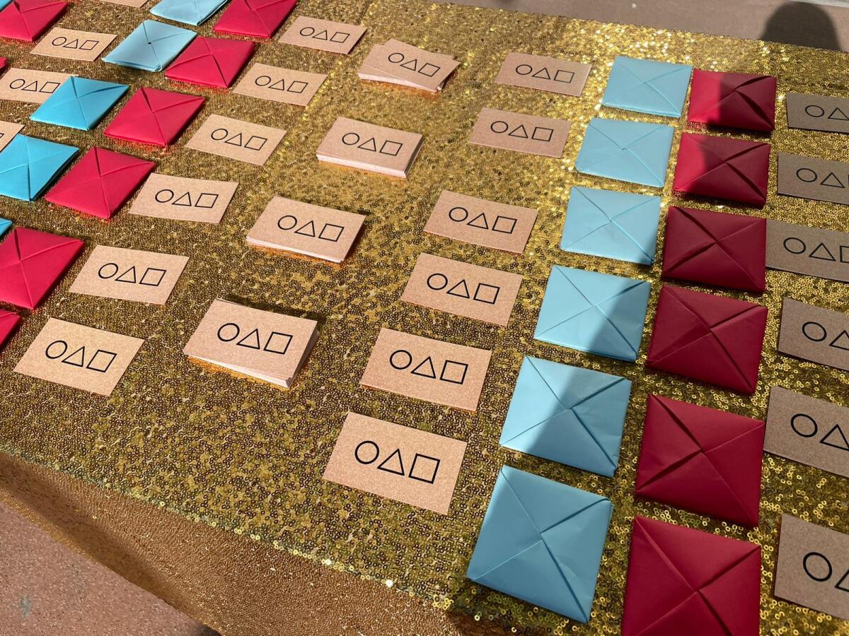 Folded tiles for ddakji are lined up beside business cards.