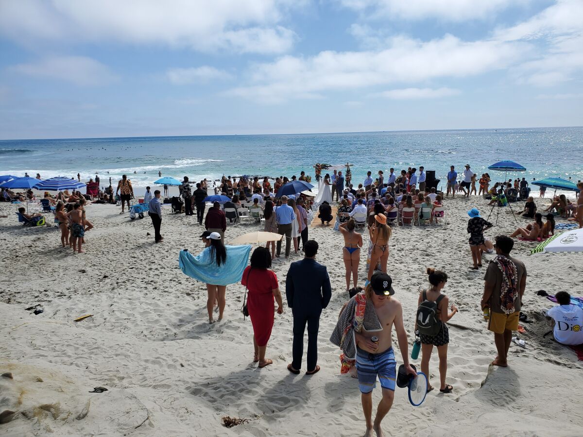 A wedding taking place July 10 on Windansea Beach is viewed from the base of the Neptune Place staircase.