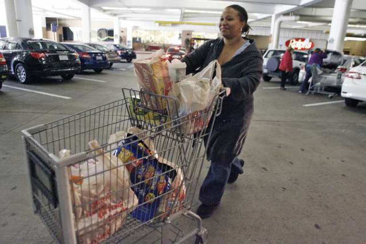 Kristine Henderson loads her car with plastic bags of groceries after shopping at Ralphs in Glendale on Tuesday.