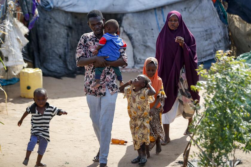 Abdikadir Omar walks to a shelter with his wife and children, who made a 12-day journey from Somalia in search of food and safety, to Dadaab refugee camp in northern Kenya, Thursday, July 13, 2023. One of the world's largest refugee camps offers a stark example of the global food security crisis with thousands of people fleeing Somalia in recent months to escape drought and extremism but finding little to eat when they arrive at the Dadaab camp in neighboring Kenya. (AP Photo/Brian Inganga)