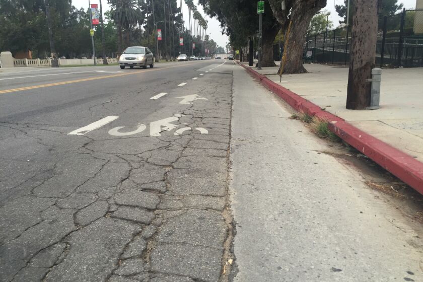 A section of the downtown L.A.-bound bike lane on Mission Road, filled with cracks and potholes, is seen across from Lincoln Park on Thursday.