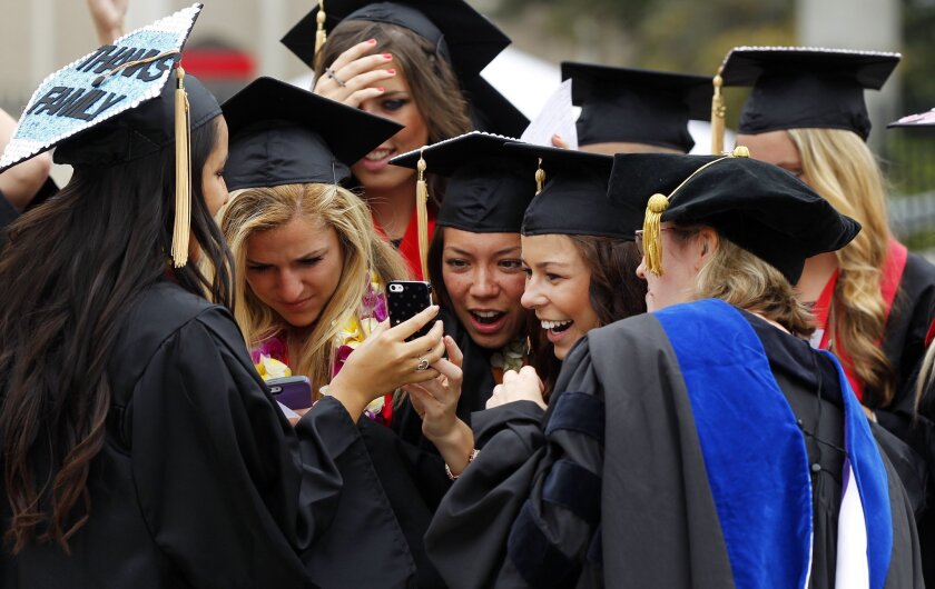 SDSU students from the College of Health and Human Services look at a picture taken before heading into graduation at Viejas Arena on Friday, kicking off a weekend of graduations at the school.