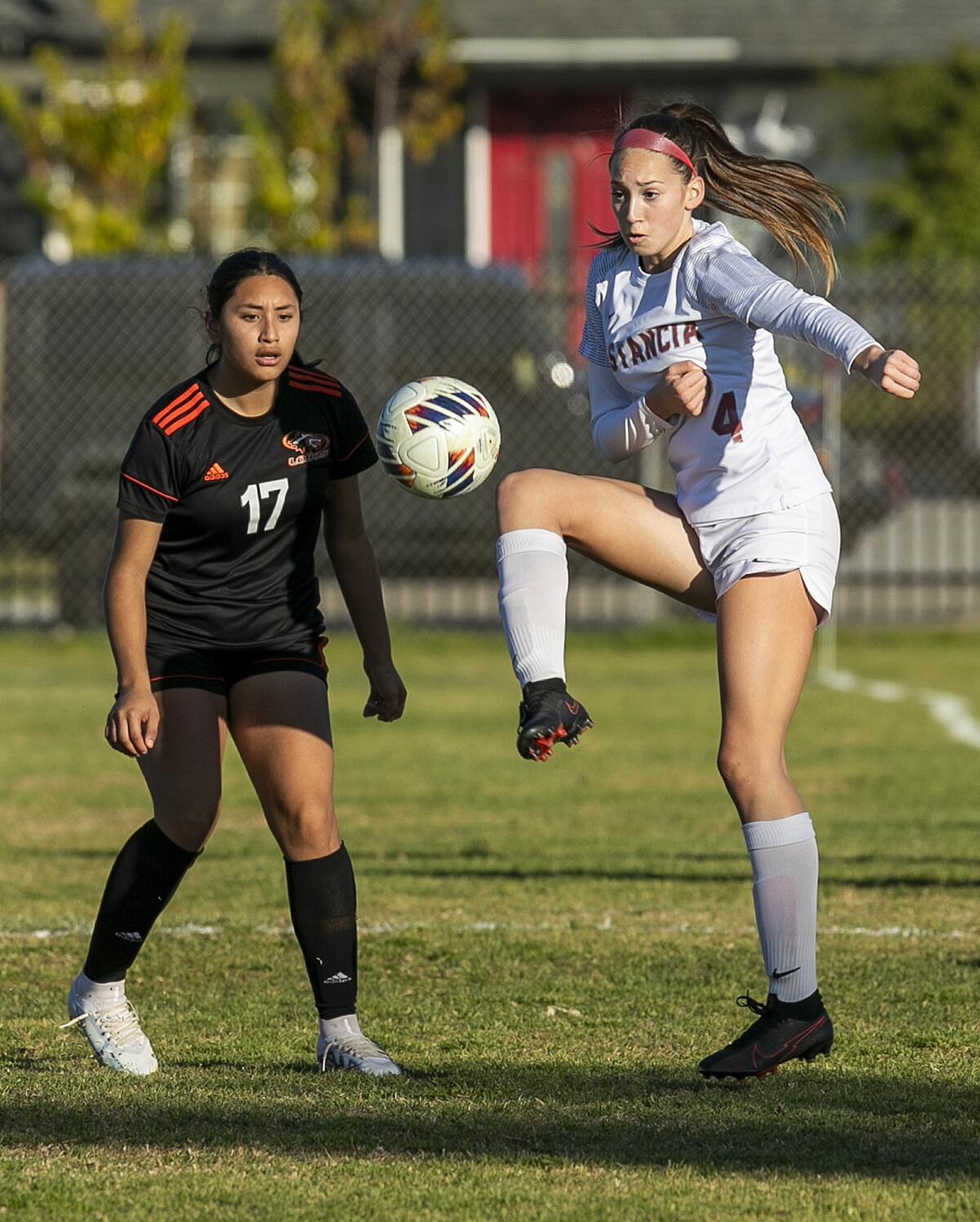 Estancia's Jana Akins handles a pass under pressure from Los Amigos' Isabel Piedra during a CIF Division 6 wildcard game.
