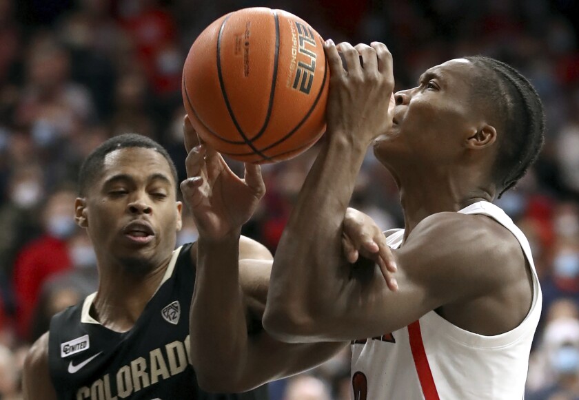 Arizona guard Bennedict Mathurin (0) gets hacked by Colorado guard Keeshawn Barthelemy (3) on his way to the basket during the first half of an NCAA college basketball game Thursday, Jan. 13, 2022 in Tucson, Ariz. (Kelly Presnell/Arizona Daily Star via AP)