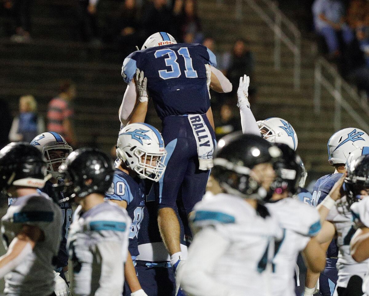 Corona del Mar's Riley Binnquist is hoisted by teammates after rushing for a one-yard first-quarter touchdown against Santiago in the first round of the CIF Southern Section Division 3 playoffs on Nov. 8 at Newport Harbor High.