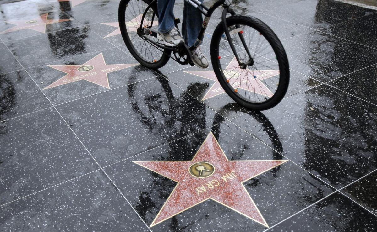 A cyclist makes his way on a wet Hollywood Boulevard.