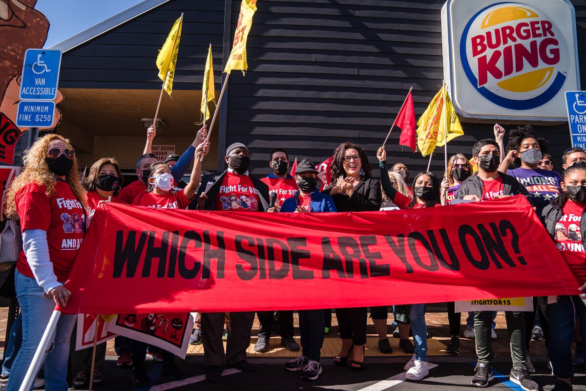 Assemblywoman Lorena Gonzalez, D-San Diego, Yusef Miller with the Racial Justice Coalition and Karina Narinan, a Burger King employee, pose for a photo along with others at a strike for better working conditions and to demand passage of AB 257 at Burger King in San Diego on Nov. 9, 2021. Photo by Ariana Drehsler for CalMatters