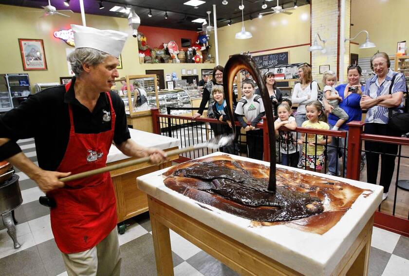 Retailers are offering entertainment to get customers in the door. Cliff Smith, left, a fudge maker at Chip's Chocolate Factory, flings the fudge while demonstrating how fudge is made.
